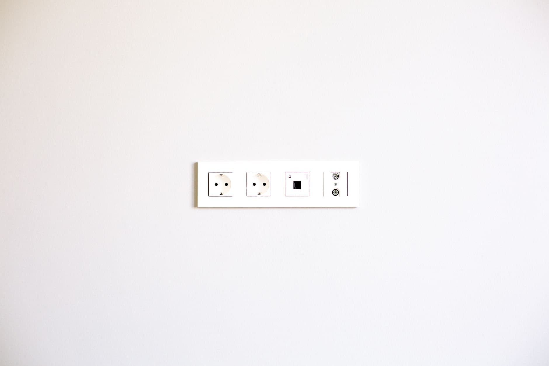 A row of sockets and data outlets on a plain white wall.