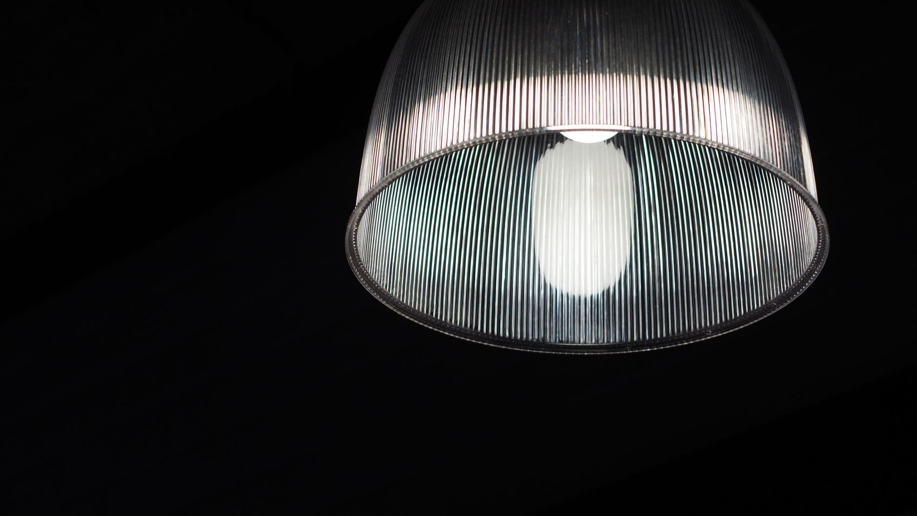 A ribbed glass lamp shade lit against a dark background.
