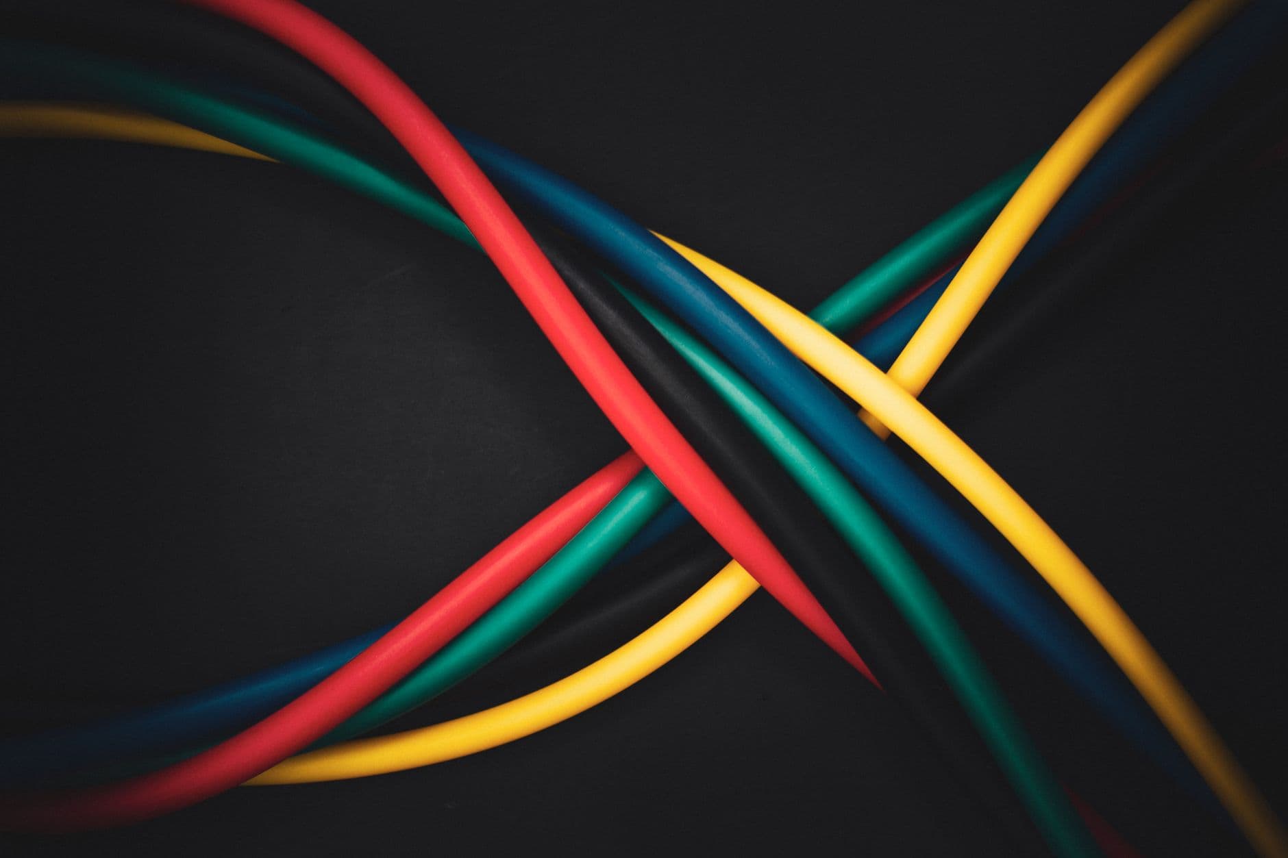 Red, blue, yellow and green insulated conductors crossing against a dark background.