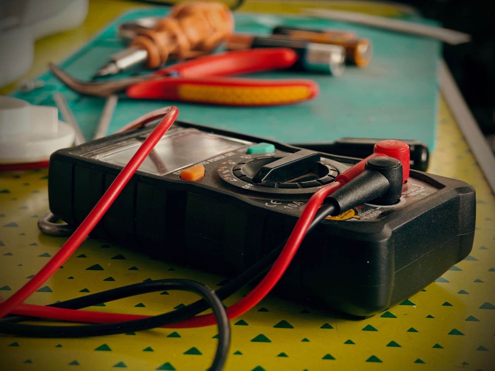 A multimeter and electrical tools on a work surface.